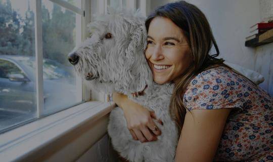Female hugging dog looking out of window