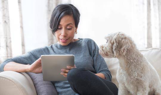 Black woman with small dog looks at tablet